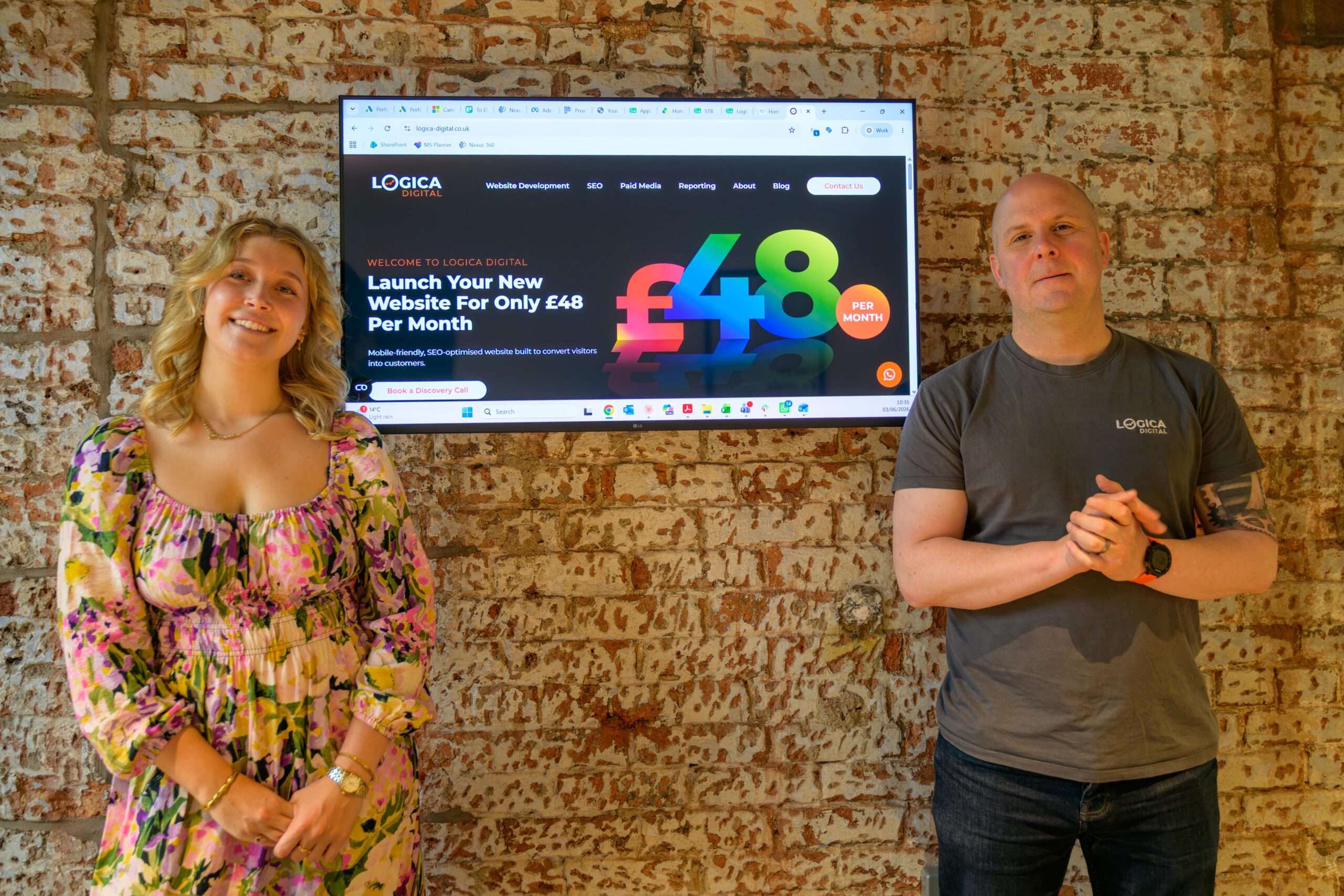 Mark and Izzy stood in front of their Website Package offering